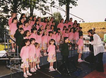Sabrina Simoni dirige il Piccolo Coro "Mariele Ventre" durante un concerto estivo.